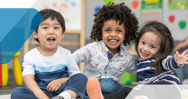 three children smiling and laughing in a classroom